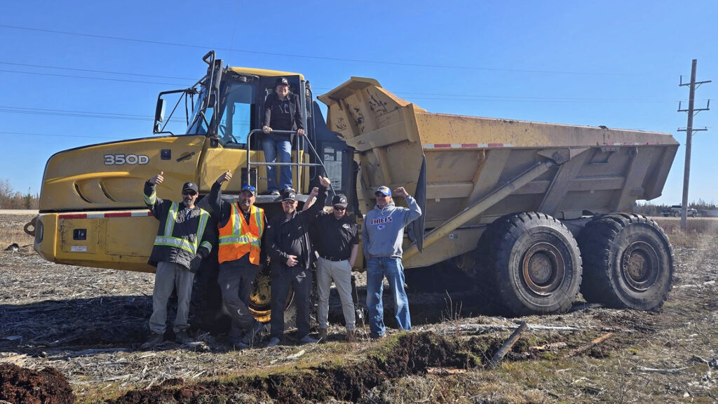 Workers standing in front of a dump truck