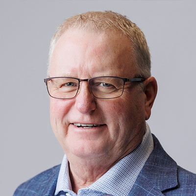 Dewayne Butterfield headshot. He has short light coloured hair, wearing glasses and is smiling.