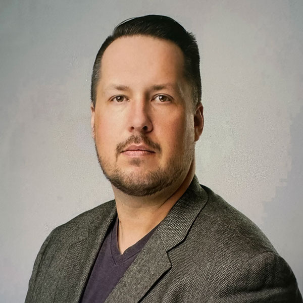 Kyle Remus headshot. He has short dark hair a goatie and has a more serious, but professional look on his face